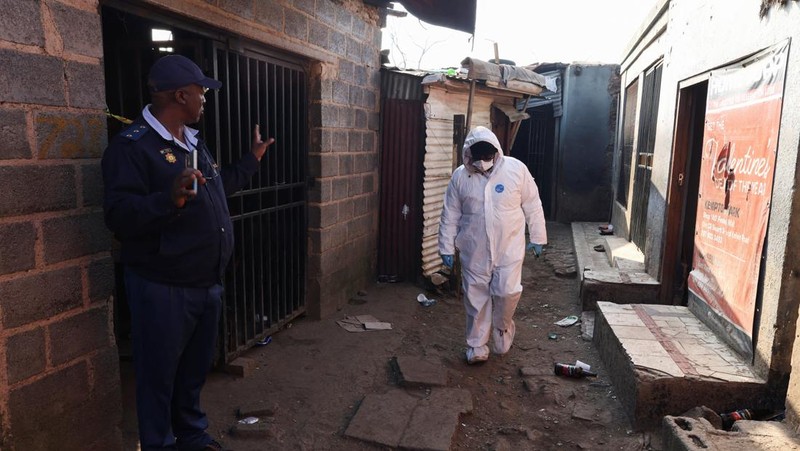 Seorang petugas polisi memberi isyarat di samping anggota tim forensik setelah, menurut polisi, seorang pria bersenjata melepaskan tembakan di permukiman kumuh di Cleveland, Johannesburg, Afrika Selatan, 10 Juni 2026. (REUTERS/Siphiwe Sibeko)