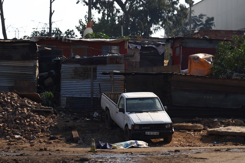 Seorang petugas polisi memberi isyarat di samping anggota tim forensik setelah, menurut polisi, seorang pria bersenjata melepaskan tembakan di permukiman kumuh di Cleveland, Johannesburg, Afrika Selatan, 10 Juni 2026. (REUTERS/Siphiwe Sibeko)