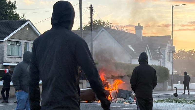 Api berkobar di tempat sampah saat demonstran anti-imigran bentrok dengan polisi di jalan Antrim, menyusul serangan pisau pada 8 Juni yang menyebabkan seorang pria terluka parah dan mendorong polisi untuk menyatakan insiden kritis, di Belfast, Irlandia Utara, 10 Juni 2026.