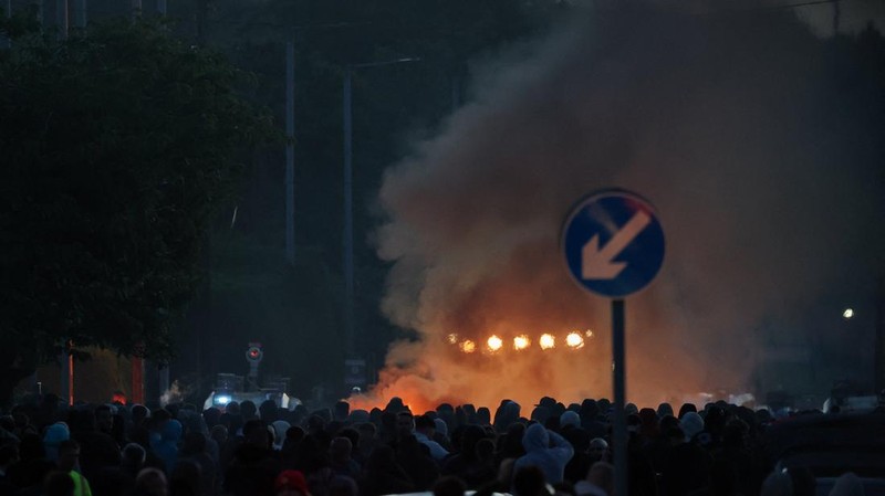 Asap mengepul saat para demonstran anti-imigran berunjuk rasa, menyusul serangan pisau pada 8 Juni yang menyebabkan seorang pria terluka parah dan mendorong polisi untuk menyatakan insiden tersebut sebagai insiden kritis, di Belfast, Irlandia Utara, 10 Juni 2026.