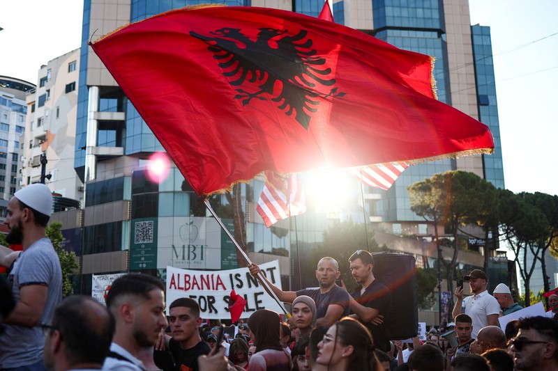 Pemandangan dari drone yang memperlihatkan para pengunjuk rasa mengibarkan bendera nasional Albania selama protes terhadap resor mewah, sebuah rencana dari perusahaan yang terkait dengan menantu Presiden AS Donald Trump, Jared Kushner, di bagian pesisir Adriatik yang sensitif terhadap lingkungan, di Tirana, Albania, 10 Juni 2026. (REUTERS/Florion Goga)