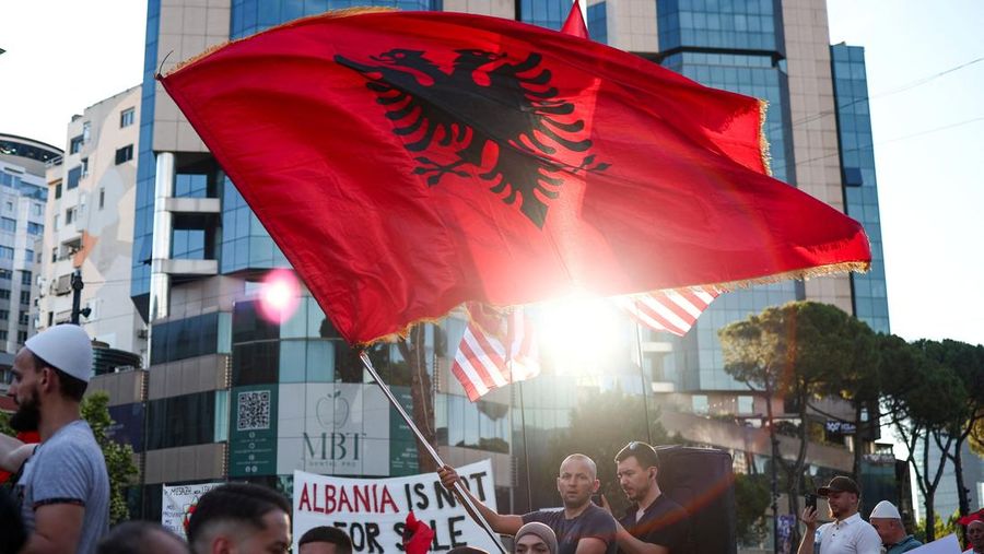 Seorang demonstran mengibarkan bendera nasional Albania selama protes terhadap resor mewah, sebuah rencana oleh perusahaan yang terkait dengan menantu Presiden AS Donald Trump, Jared Kushner, di bagian pesisir Adriatik yang sensitif terhadap lingkungan, di Tirana, Albania, 10 Juni 2026.