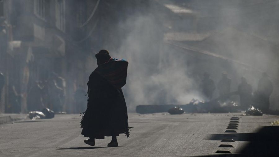 Seorang wanita Aymara berjalan menembus asap dari api unggun selama protes yang menyerukan pengunduran diri Presiden Bolivia Rodrigo Paz, menyusul protes dan blokade selama berminggu-minggu yang menyebabkan kekurangan makanan, bahan bakar, dan obat-obatan, di La Paz, Bolivia, 10 Juni 2026.