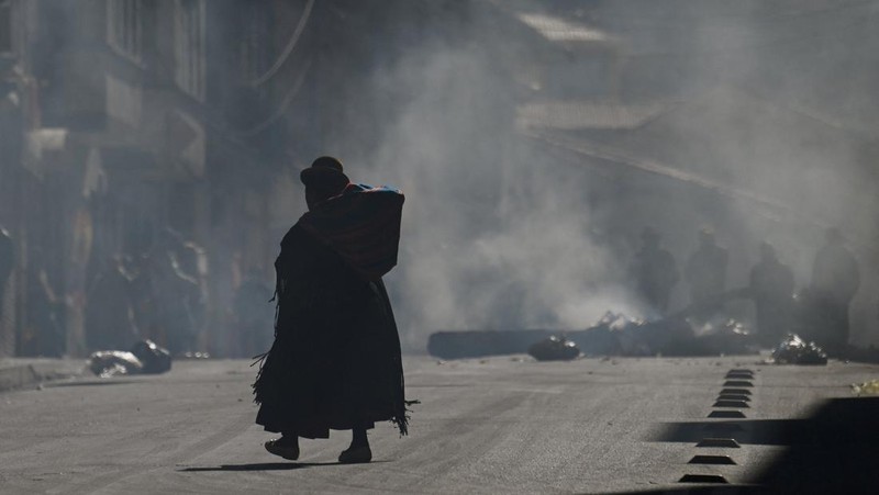 Seorang wanita Aymara berjalan menembus asap dari api unggun selama protes yang menyerukan pengunduran diri Presiden Bolivia Rodrigo Paz, menyusul protes dan blokade selama berminggu-minggu yang menyebabkan kekurangan makanan, bahan bakar, dan obat-obatan, di La Paz, Bolivia, 10 Juni 2026.