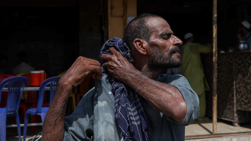 Allah Bux, 30 tahun, seorang buruh, menyeka keringat dengan syalnya setelah menurunkan barang dagangan di luar sebuah kafe pada hari musim panas yang terik di Karachi, Pakistan. 11 Juni 2026.