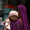 Faizan yang berusia satu tahun tidur siang di pundak ibunya, dengan kepalanya ditutupi syal untuk menghalangi sinar matahari pada hari musim panas yang terik di Karachi, Pakistan, 10 Juni 2026. (REUTERS/Akhtar Soomro)