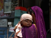 Faizan yang berusia satu tahun tidur siang di pundak ibunya, dengan kepalanya ditutupi syal untuk menghalangi sinar matahari pada hari musim panas yang terik di Karachi, Pakistan, 10 Juni 2026. (REUTERS/Akhtar Soomro)