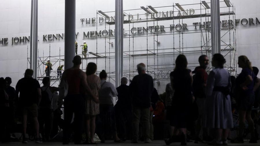 Orang-orang memperhatikan para pekerja saat mereka memasang perancah untuk melepas tulisan dari fasad John F. Kennedy Memorial Center for the Performing Arts, menyusul perintah hakim federal untuk menghapus nama Presiden AS Donald Trump dari institusi tersebut, di Washington, D.C., AS, 12 Juni 2026.