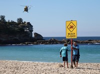 Para petugas penjaga pantai memasang tanda bertuliskan "Pantai Ditutup" setelah serangan hiu di Pantai Coogee di Sydney, Australia, 13 Juni 2026. (REUTERS/Hollie Adams)