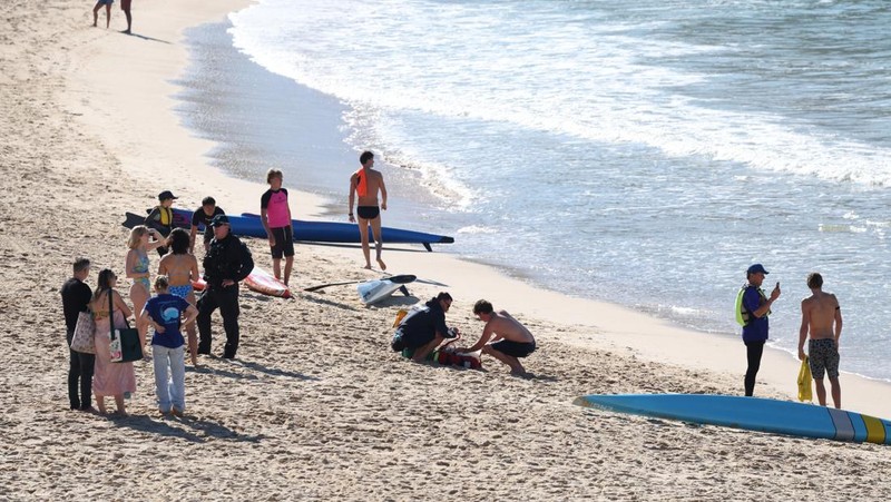 Seorang petugas polisi berbicara kepada orang-orang setelah serangan hiu di Pantai Coogee di Sydney, Australia, 13 Juni 2026.