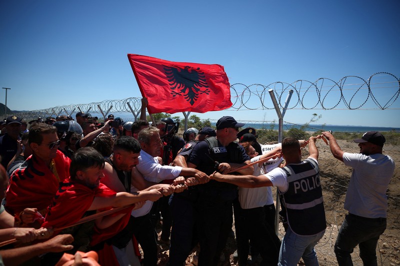 Para pengunjuk rasa yang mengatakan tanah mereka telah diambil secara tidak adil, merobohkan pagar tempat resor wisata akan dibangun di tepi pantai Adriatik, di Rrjoll, dekat Shkodra, Albania, 13 Juni 2026. (REUTERS/Florion Goga)