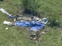 Puing-puing pesawat tergeletak di lapangan di sebelah Bandara Memorial Butler setelah sebuah pesawat yang membawa penerjun payung jatuh di Butler, Missouri, AS, pada 14 Juni 2026, dalam gambar diam dari video. (ABC Affiliate KMBC via REUTERS)