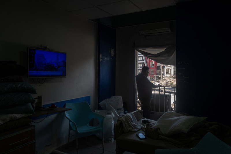 Youssef Fares, 90, whose home of more than 70 years was damaged in an Israeli airstrike, stands at the window of a hospital room where he has taken shelter, overlooking buildings damaged by Israeli strikes, following a deal between the United States and Iran, in Tyre, southern Lebanon, June 16, 2026. REUTERS/Zohra Bensemra.