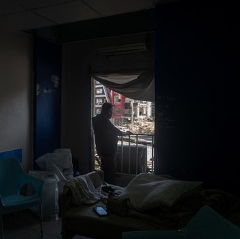 Youssef Fares, 90, whose home of more than 70 years, was reportedly damaged by an Israeli airstrike, stands at the window of a hospital room where he has taken shelter, overlooking buildings damaged by Israeli strikes, following a deal between the U.
