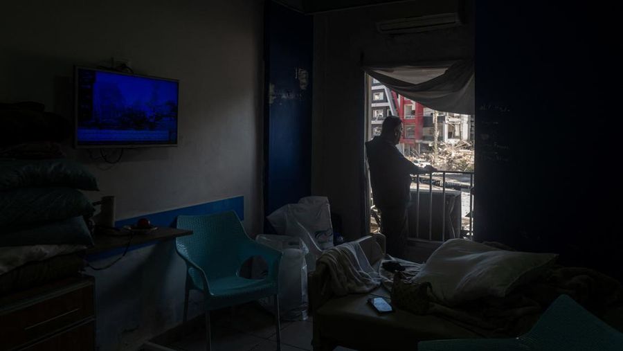 Youssef Fares, 90, whose home of more than 70 years, was reportedly damaged by an Israeli airstrike, stands at the window of a hospital room where he has taken shelter, overlooking buildings damaged by Israeli strikes, following a deal between the U.