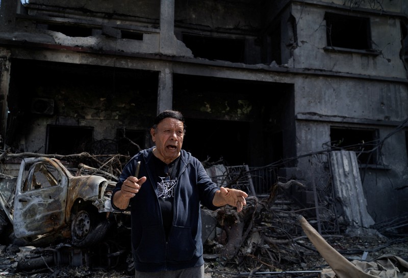 Youssef Fares, 90, whose home of more than 70 years was damaged in an Israeli airstrike, stands at the window of a hospital room where he has taken shelter, overlooking buildings damaged by Israeli strikes, following a deal between the United States and Iran, in Tyre, southern Lebanon, June 16, 2026. REUTERS/Zohra Bensemra.