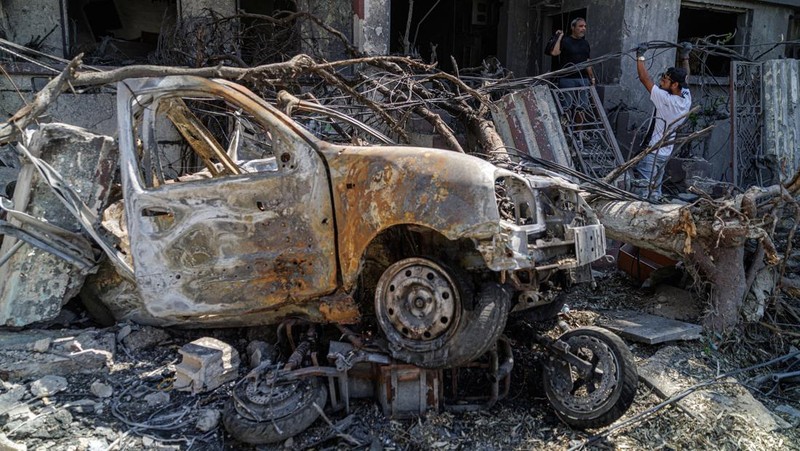 Ahmad Fares, 40, an online antique seller, walks out of his family home of more than 70 years, damaged in an Israeli airstrike, as his friend Sharif Safiaddine, 33, attempts to fix electrical cables, in Tyre, southern Lebanon, June 16, 2026. REUTERS/