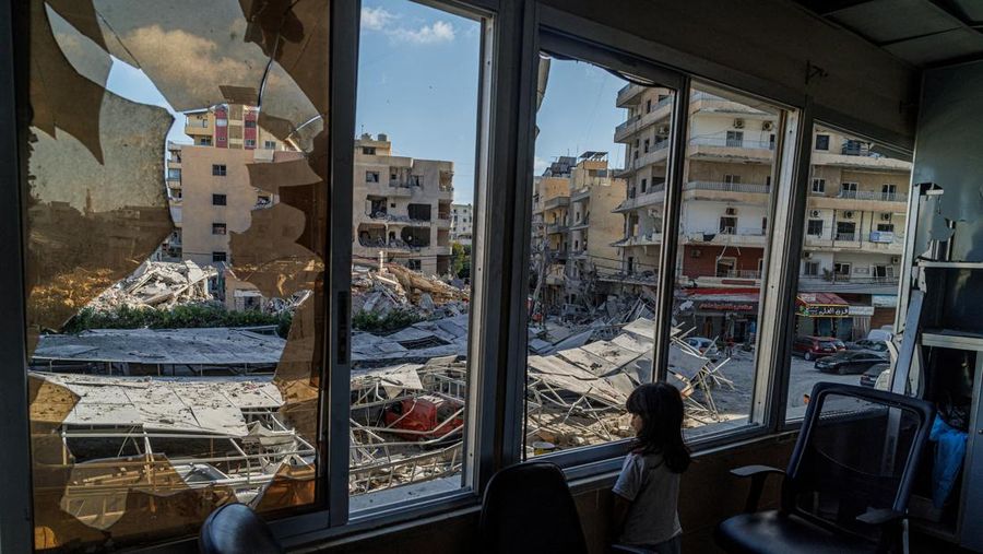 A displaced girl stands at the broken window of Jabal Amel hospital where she has taken shelter with her family, overlooking buildings damaged by Israeli strikes, following a deal between the U.S. and Iran, in Tyre, southern Lebanon, June 16, 2026. R