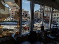 A displaced girl stands at the broken window of Jabal Amel hospital where she has taken shelter with her family, overlooking buildings damaged by Israeli strikes, following a deal between the U.S. and Iran, in Tyre, southern Lebanon, June 16, 2026. R