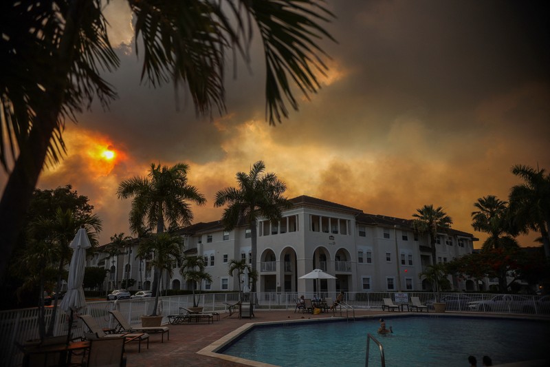 Seorang wanita menutupi wajahnya saat menyaksikan kebakaran semak yang terjadi relatif dekat dengan lingkungan perumahan Doral di Miami, Florida, AS, 16 Juni 2026. (REUTERS/Maria Alejandra Cardona)
