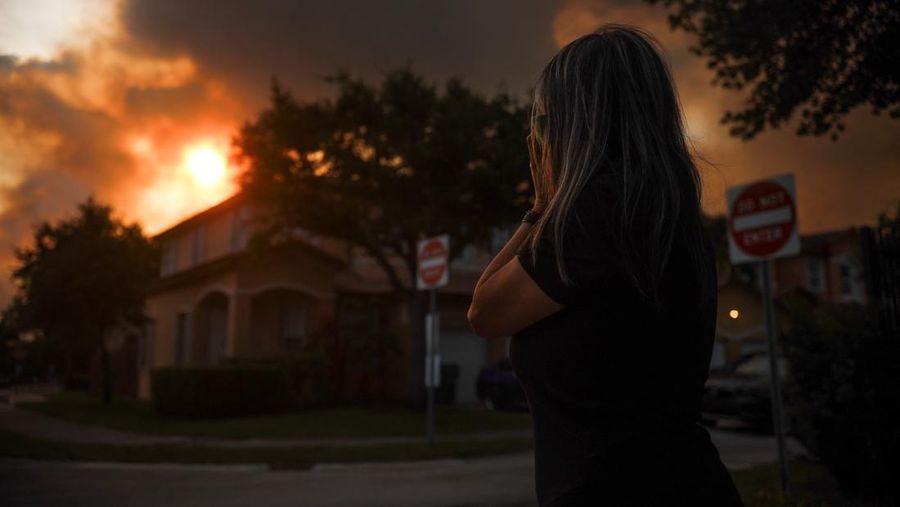 Seorang wanita menutupi wajahnya saat menyaksikan kebakaran semak yang terjadi relatif dekat dengan lingkungan perumahan Doral di Miami, Florida, AS, 16 Juni 2026.