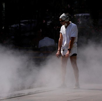 A man cools off in a water mister on the Place de la Republique in Paris as a heatwave hits a large part of France, June 18, 2026. REUTERS/Alice Sacco
