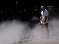 A man cools off in a water mister on the Place de la Republique in Paris as a heatwave hits a large part of France, June 18, 2026. REUTERS/Alice Sacco