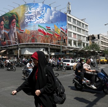 Orang-orang melewati papan reklame yang menggambarkan mendiang pemimpin Revolusi Islam, Ayatollah Ruhollah Khomeini, dan mendiang Pemimpin Tertinggi Iran, Ayatollah Ali Khamenei, di sebuah jalan di Teheran, Iran, (6/6/2026).  (via REUTERS/Majid Asgar