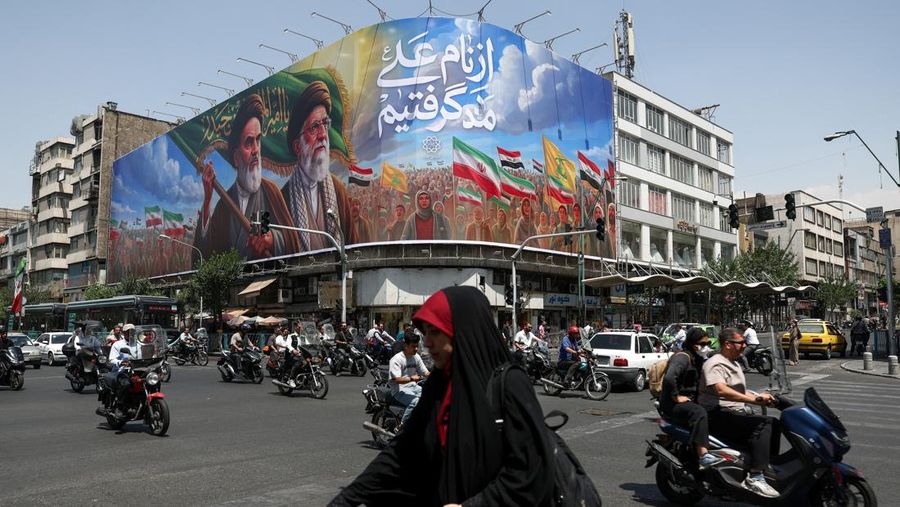 Orang-orang melewati papan reklame yang menggambarkan mendiang pemimpin Revolusi Islam, Ayatollah Ruhollah Khomeini, dan mendiang Pemimpin Tertinggi Iran, Ayatollah Ali Khamenei, di sebuah jalan di Teheran, Iran, (6/6/2026).  (via REUTERS/Majid Asgar