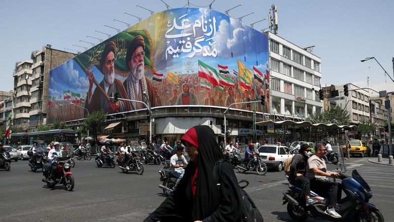 Orang-orang melewati papan reklame yang menggambarkan mendiang pemimpin Revolusi Islam, Ayatollah Ruhollah Khomeini, dan mendiang Pemimpin Tertinggi Iran, Ayatollah Ali Khamenei, di sebuah jalan di Teheran, Iran, (6/6/2026).  (via REUTERS/Majid Asgar