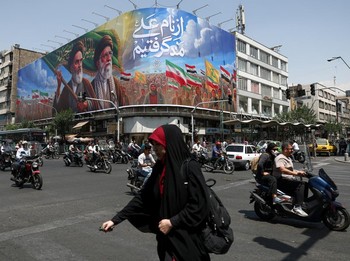 Orang-orang melewati papan reklame yang menggambarkan mendiang pemimpin Revolusi Islam, Ayatollah Ruhollah Khomeini, dan mendiang Pemimpin Tertinggi Iran, Ayatollah Ali Khamenei, di sebuah jalan di Teheran, Iran, (6/6/2026).  (via REUTERS/Majid Asgar