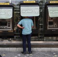 Seorang pria menggunakan ATM Bank Melli Iran di depan sebuah bank di Teheran, Iran, 17 Juni 2026. (via REUTERS/Majid Asgaripour)
