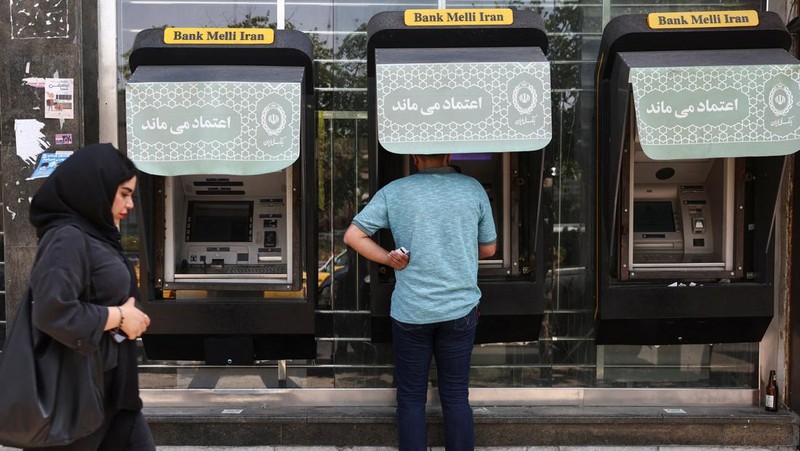 Seorang pria menggunakan ATM Bank Melli Iran di depan sebuah bank di Teheran, Iran, 17 Juni 2026. (via REUTERS/Majid Asgaripour)