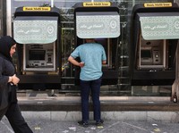 Seorang pria menggunakan ATM Bank Melli Iran di depan sebuah bank di Teheran, Iran, 17 Juni 2026. (via REUTERS/Majid Asgaripour)