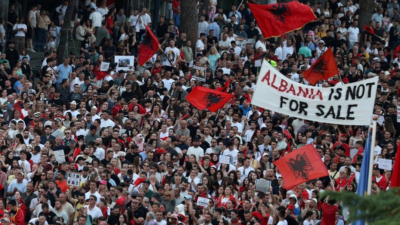 Warga di Albania melakukan demonstrasi menolak pembangunan resor terkait dengan keluarga Presiden Amerika Serikat (AS) Donald Trump, Minggu (21/6/2026). Demonstrasi yang dimulai hampir tiga minggu lalu itu semakin membesar. (REUTERS/Florion Goga)