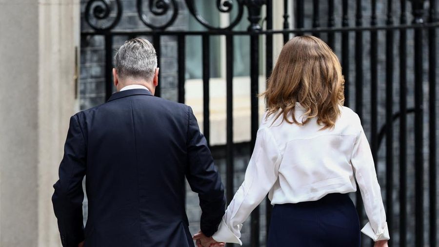 Perdana Menteri Inggris Keir Starmer berjalan sambil bergandengan tangan dengan istrinya Victoria, setelah mengumumkan jadwal pengunduran dirinya, di luar 10 Downing Street, London, Inggris, 22 Juni 2026. (REUTERS/Toby Shepheard)