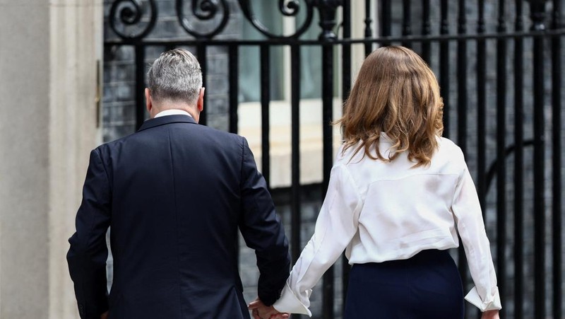 Perdana Menteri Inggris Keir Starmer berjalan sambil bergandengan tangan dengan istrinya Victoria, setelah mengumumkan jadwal pengunduran dirinya, di luar 10 Downing Street, London, Inggris, 22 Juni 2026. (REUTERS/Toby Shepheard)