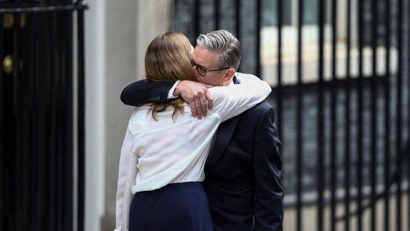 Perdana Menteri Inggris Keir Starmer memeluk istrinya Victoria, saat ia mengumumkan jadwal pengunduran dirinya, di luar 10 Downing Street, London, Inggris, 22 Juni 2026. (REUTERS/Toby Shepheard)