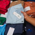 Petugas Direktorat Jenderal Kekayaan Intelektual (DJKI) menata produk menggunakan merek Lacoste tanpa hak saat konferensi pers di Jakarta, Senin (22/6/2026). (CNBC Indonesia/Faisal Rahman)