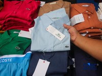 Petugas Direktorat Jenderal Kekayaan Intelektual (DJKI) menata produk menggunakan merek Lacoste tanpa hak saat konferensi pers di Jakarta, Senin (22/6/2026). (CNBC Indonesia/Faisal Rahman)