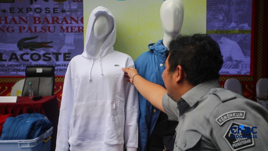 Petugas Direktorat Jenderal Kekayaan Intelektual (DJKI) menata produk menggunakan merek Lacoste tanpa hak saat konferensi pers di Jakarta, Senin (22/6/2026). (CNBC Indonesia/Faisal Rahman)