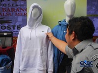 Petugas Direktorat Jenderal Kekayaan Intelektual (DJKI) menata produk menggunakan merek Lacoste tanpa hak saat konferensi pers di Jakarta, Senin (22/6/2026). (CNBC Indonesia/Faisal Rahman)