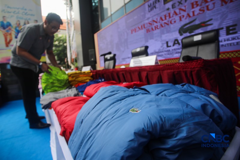 Petugas Direktorat Jenderal Kekayaan Intelektual (DJKI) menata produk menggunakan merek Lacoste tanpa hak saat konferensi pers di Jakarta, Senin (22/6/2026). (CNBC Indonesia/Faisal Rahman)