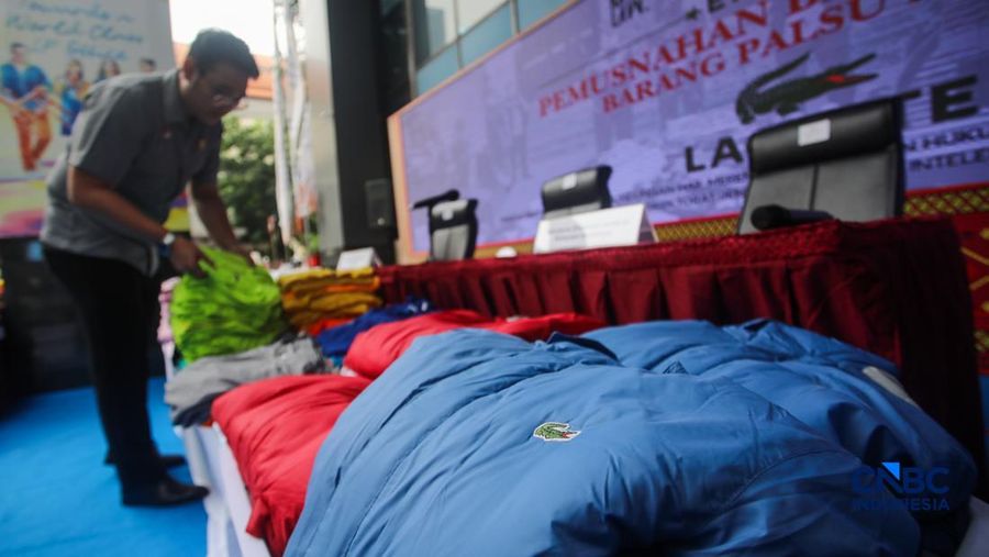 Petugas Direktorat Jenderal Kekayaan Intelektual (DJKI) menata produk menggunakan merek Lacoste tanpa hak saat konferensi pers di Jakarta, Senin (22/6/2026).