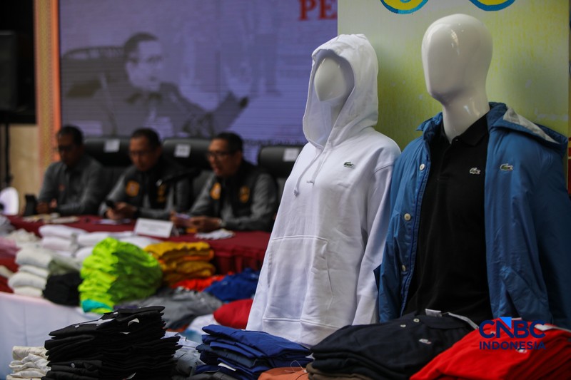 Petugas Direktorat Jenderal Kekayaan Intelektual (DJKI) menata produk menggunakan merek Lacoste tanpa hak saat konferensi pers di Jakarta, Senin (22/6/2026). (CNBC Indonesia/Faisal Rahman)