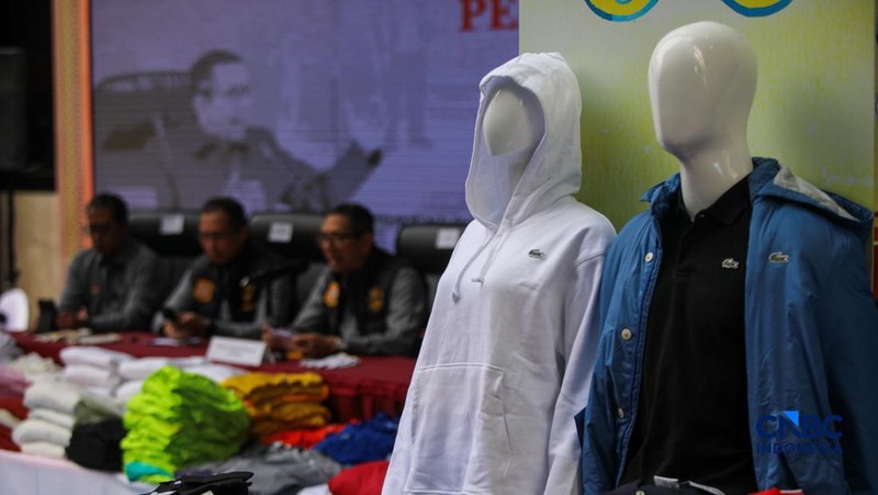 Petugas Direktorat Jenderal Kekayaan Intelektual (DJKI) menata produk menggunakan merek Lacoste tanpa hak saat konferensi pers di Jakarta, Senin (22/6/2026).