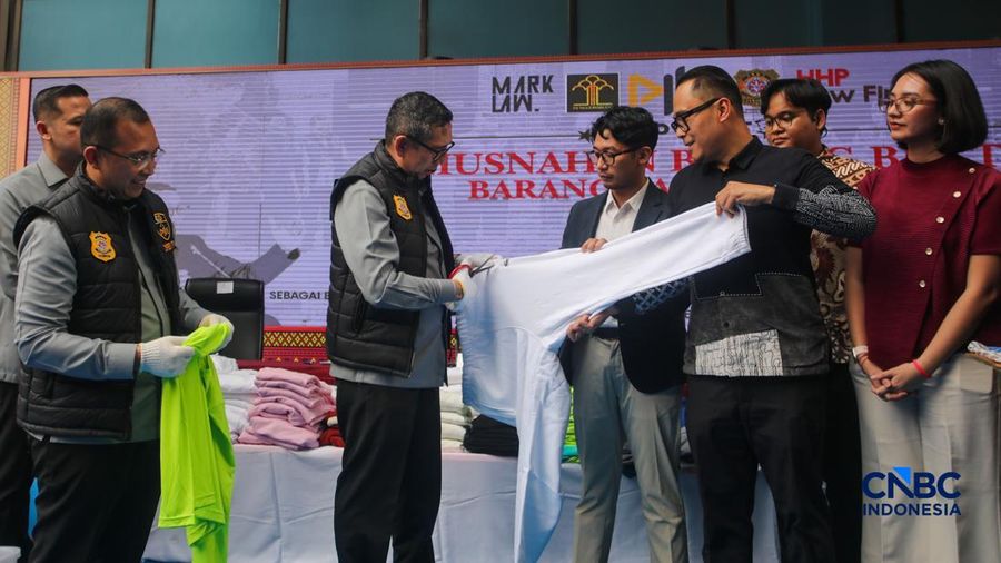 Petugas Direktorat Jenderal Kekayaan Intelektual (DJKI) menata produk menggunakan merek Lacoste tanpa hak saat konferensi pers di Jakarta, Senin (22/6/2026).