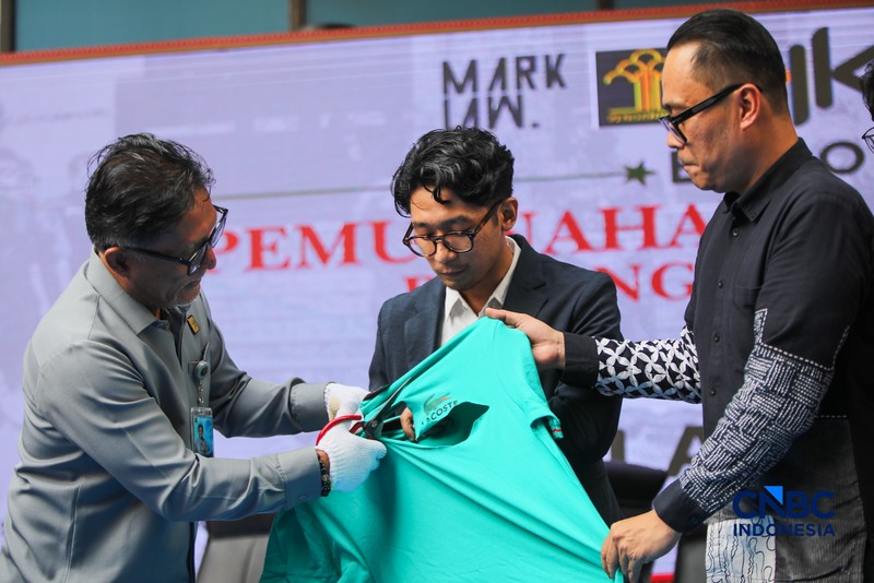 Petugas Direktorat Jenderal Kekayaan Intelektual (DJKI) menata produk menggunakan merek Lacoste tanpa hak saat konferensi pers di Jakarta, Senin (22/6/2026). (CNBC Indonesia/Faisal Rahman)