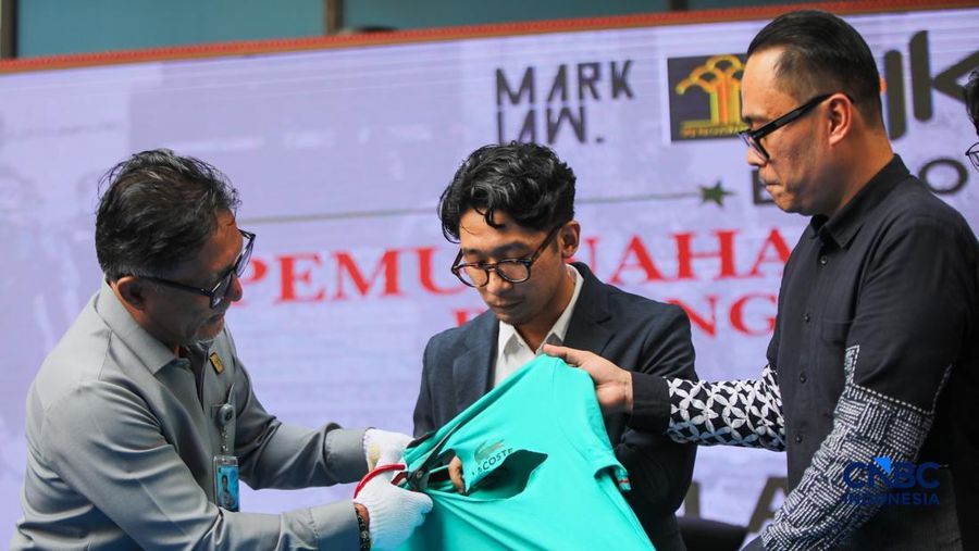 Petugas Direktorat Jenderal Kekayaan Intelektual (DJKI) menata produk menggunakan merek Lacoste tanpa hak saat konferensi pers di Jakarta, Senin (22/6/2026).