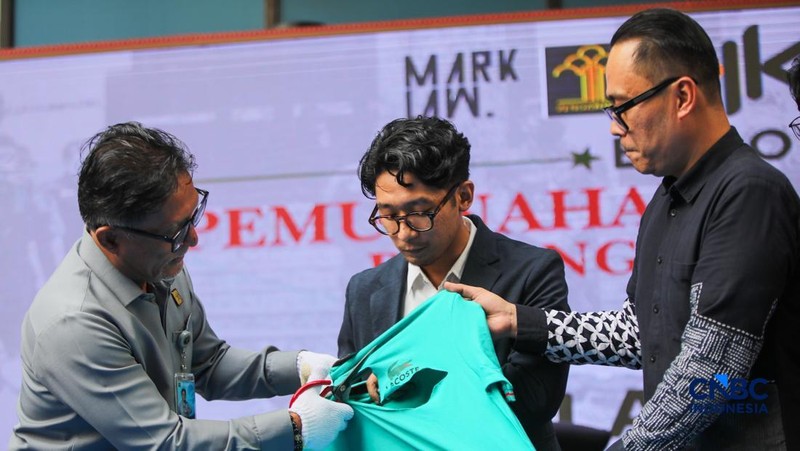 Petugas Direktorat Jenderal Kekayaan Intelektual (DJKI) menata produk menggunakan merek Lacoste tanpa hak saat konferensi pers di Jakarta, Senin (22/6/2026).